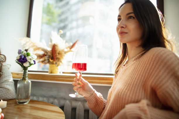 明媚的日子里，美丽的女人拿着红酒坐在咖啡馆里图片下载