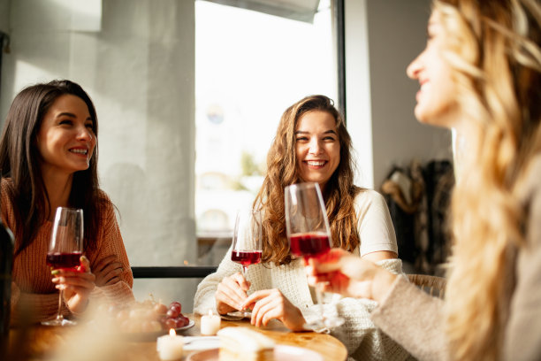 三个美丽的女人坐在咖啡馆里，一边聊天一边喝着红酒。周末聚会图片下载