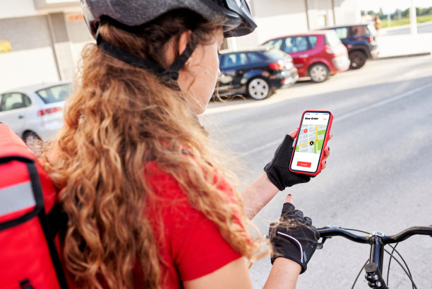 一个骑自行车的送货女孩用她的手机检查下一个货物的地址图片下载