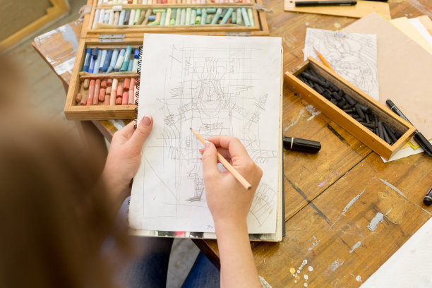 艺术家用石墨笔在纸上画了一幅素描。桌子上的艺术家有不同的绘画用品图片下载