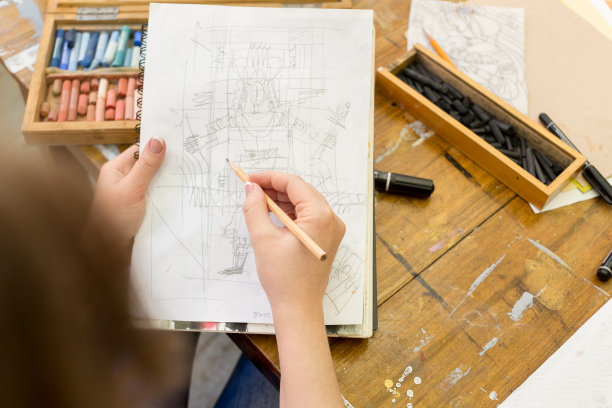 艺术家用石墨笔在纸上画了一幅素描。桌子上的艺术家有不同的绘画用品图片下载