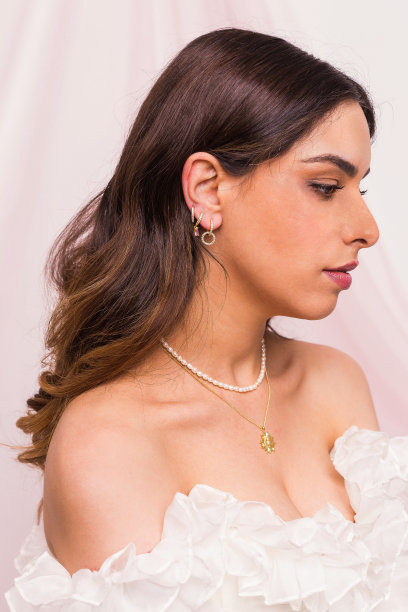 美丽的年轻女子戴着珍珠和金项链和金耳环图片下载