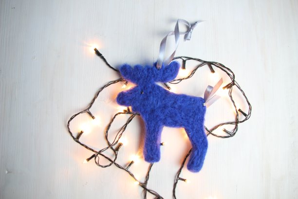 毛毡羊毛蓝色玩具麋鹿或麋鹿与轻的花环在白色背景图片下载