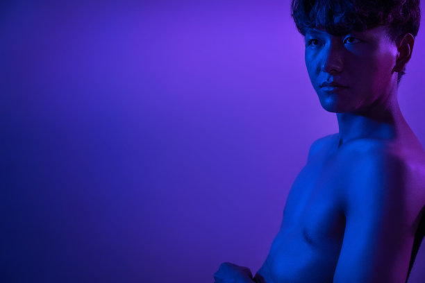 紫色灯光下举着哑铃的运动员图片下载