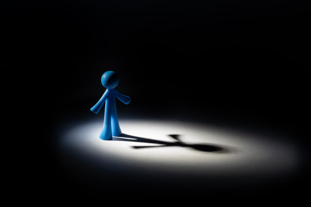 一个象征性的人物雕像站在一个光圈里，投下长长的影子图片下载