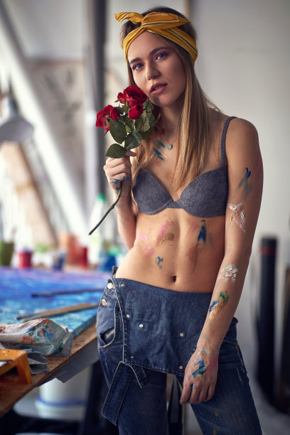 一名性感迷人的女艺术家在她的工作室里与玫瑰摆造型，休息时绘画。艺术、绘画、工作室图片下载