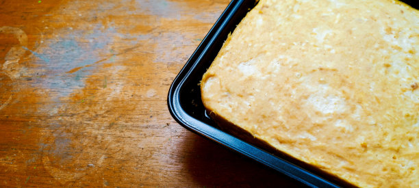 在木桌上的方形铁制容器中蒸熟或烤熟的面团。图片下载