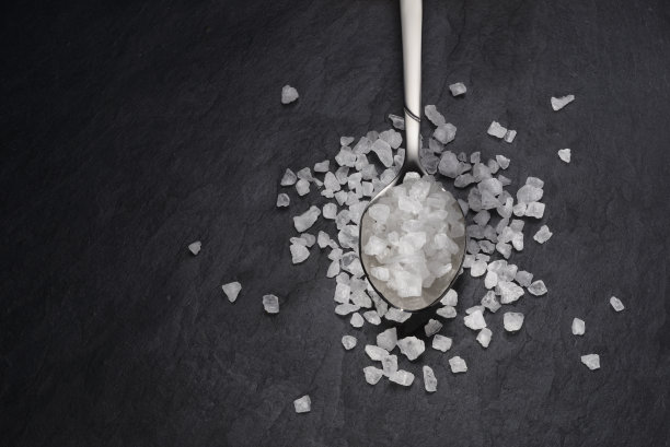 茶匙粗海盐在黑色石板背景。图片下载
