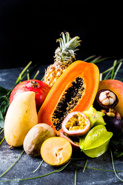 异域水果与木瓜，菠萝，石榴在黑暗的背景与文字的地方图片下载