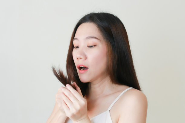 亚洲美女看她的头发，损伤头发，头发问题，头发干燥与担心和震惊。图片下载