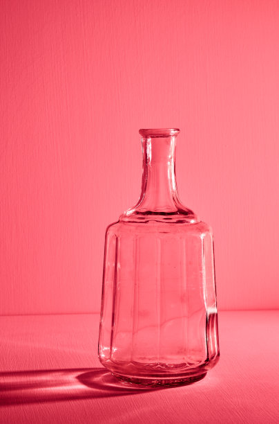 空开的玻璃瓶，有复印空间。图形静物与光和阴影在红光。玻璃容器、可回收材料或酒精的概念。大创意的花瓶。开瓶图片下载