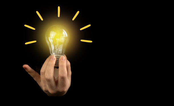 女商人手里拿着一个灯泡，背景是黑色的，有复印的空间图片下载