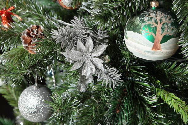 圣诞树上的圣诞装饰。一个五彩的球，一个花环和红色的装饰在绿色的圣诞树的树枝上，洒着雪花。特写镜头。图片下载