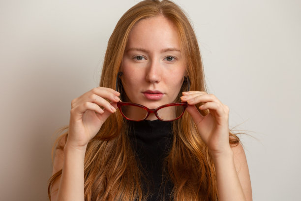 美丽年轻的红发女孩戴着眼镜看着相机，微笑着图片下载