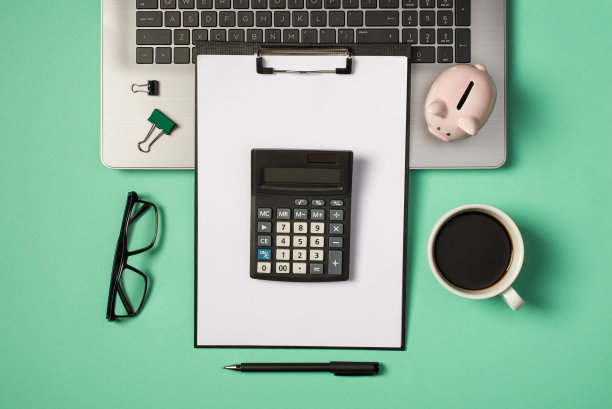 顶部视图照片的绿色和黑色的活页夹夹小猪在灰色笔记本电脑眼镜杯饮料钢笔和计算器在黑色的剪贴板文件夹与纸页孤立的蓝绿色背景图片下载