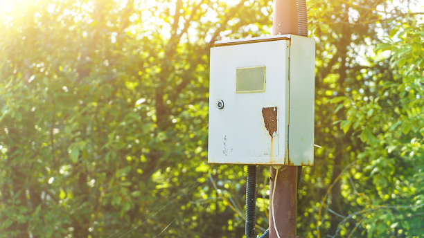 街上的电控箱。户外控制开关和电气开关。在一个晴朗的夏日，灰色的铰链把电源安装在一根铁柱子上图片下载