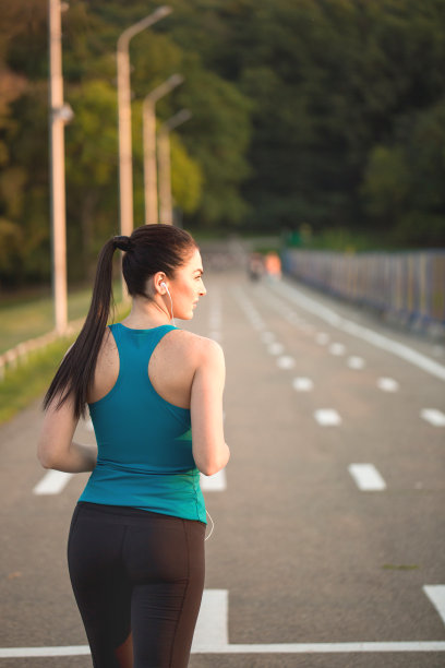 年轻漂亮的女孩穿着蓝色的t恤在新鲜的空气中做运动。户外锻炼。概念是健康的生活方式。图片下载