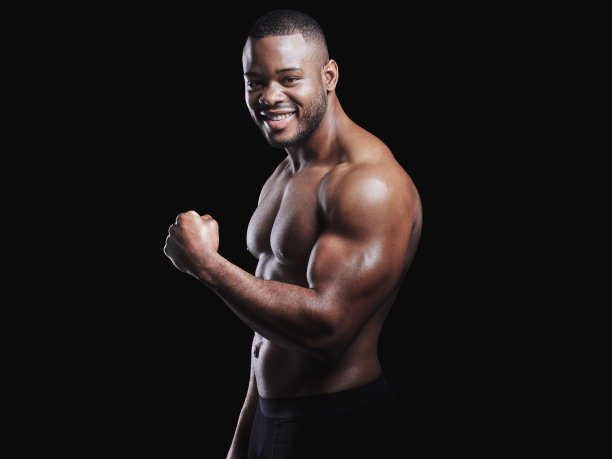 一个身材匀称的年轻人在黑色背景下摆姿势的工作室肖像图片下载