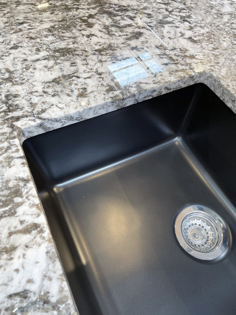 黑色复合厨房水槽与白色和灰色花岗岩大理石台面，集成花岗岩排水板与沟槽，隧道和排水，高架视野，聚焦前景图片下载