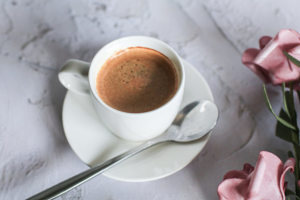 白色桌面背景上有玫瑰图案的咖啡杯。情人节与短信的地方。复古的照片。空间的文本图片下载