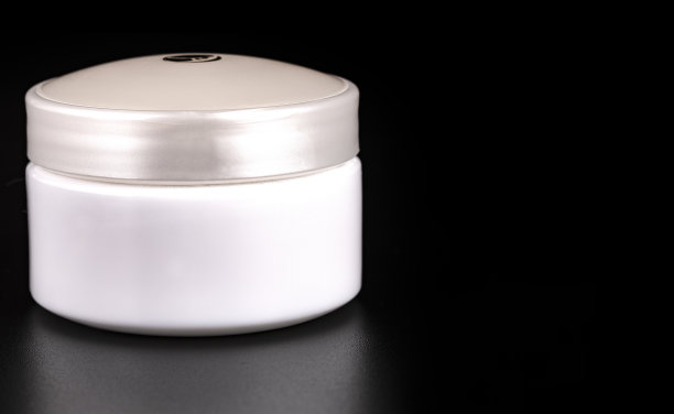 黑色背景下的美容霜容器特写图片下载