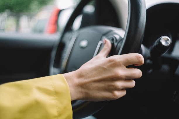 近距离照片的不认识的女孩，谁驾驶汽车和按按钮的方向盘。旅行的概念。选择性聚焦手臂。图片下载