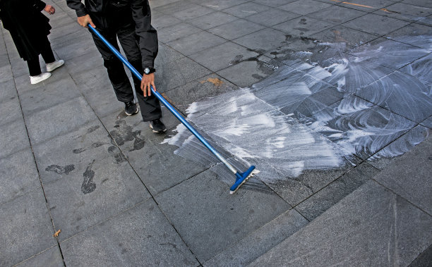 一名员工正在用拖把清洗人行道表面。这名男子用泡沫和水清洗。图片下载