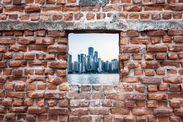 废弃的旧砖墙窗户与大海和摩天大楼的景色。城市化图片下载