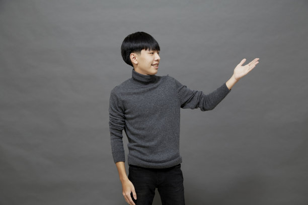 灰色背景下快乐微笑的年轻男学生图片下载