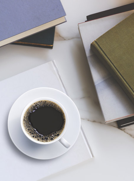 陶瓷杯里的黑咖啡平铺在白色的书上，大理石桌面上堆放着各种旧课本图片下载