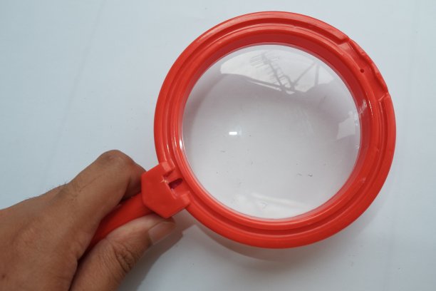 一位亚洲男性手持红色放大镜图片下载