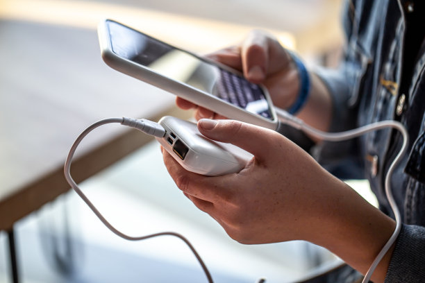 一个女人手里拿着一个充电宝和一个电话。图片下载