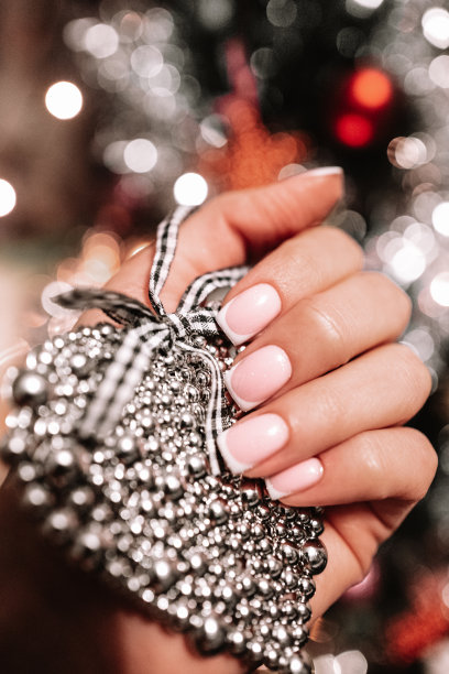 女手捧银心，倚着圣诞树散景灯。图片下载