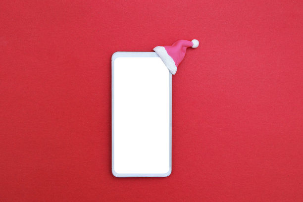 模拟智能手机在圣诞老人的帽子在红色背景。极简圣诞网上销售概念图片下载