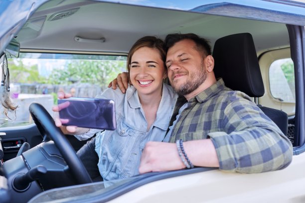 幸福的夫妻用智能手机自拍，夫妻坐在车里图片下载