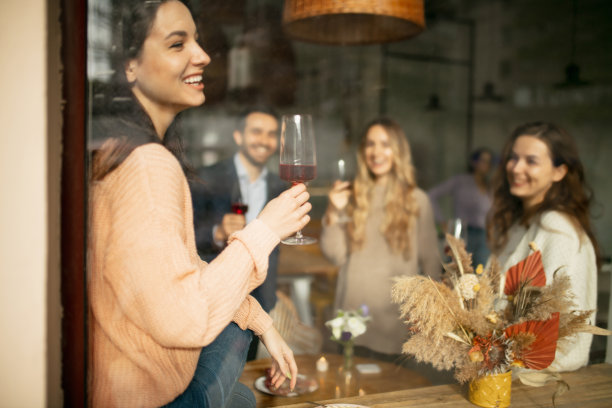 一幅年轻女子的剪裁肖像，手拿酒杯，在温暖阳光明媚的日子里与朋友在咖啡馆见面图片下载