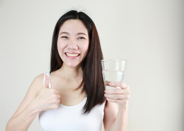 亚洲快乐微笑美女手持水杯，白色背景上竖起大拇指图片下载