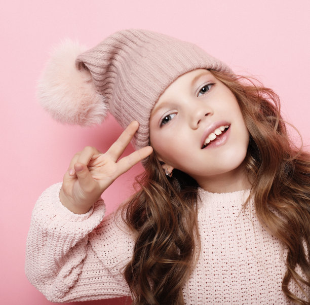 人物、童年和时尚理念:小女孩戴着粉红色的冬季帽子，穿着粉红色背景的毛衣图片下载