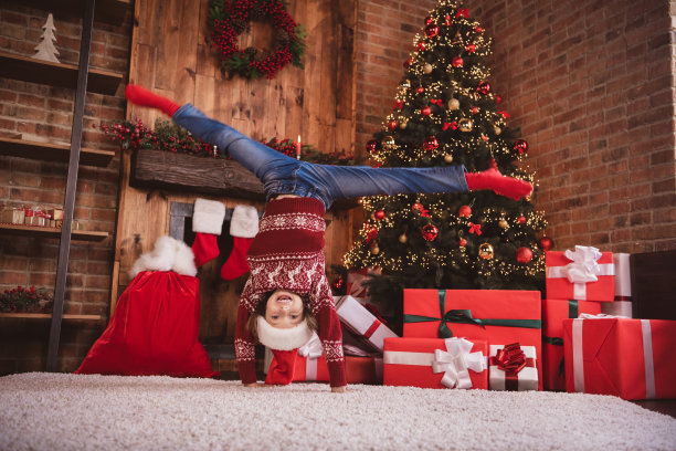 小男孩的照片杂技运动女孩倒立双手穿套头圣诞老人头戴袜子在室内图片下载