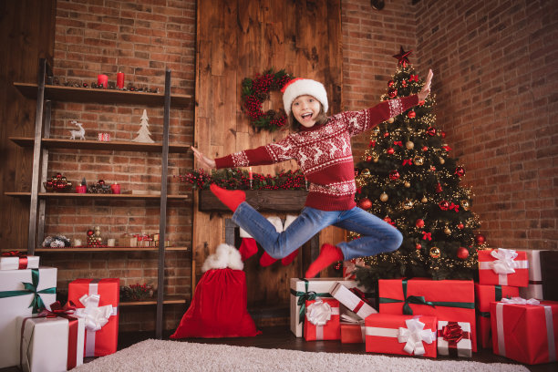 照片的运动小孩子无忧无虑的女孩享受飞行跳跃有乐趣穿套头衫圣诞老人头戴袜子在室内图片下载