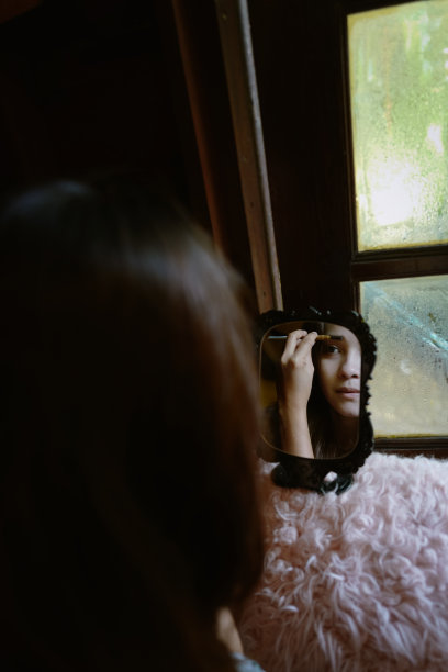 从镜子里映照出来的年轻女子正在为她化妆，使她焕然一新图片下载