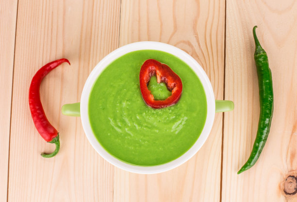 绿奶油汤和两个红辣椒。图片下载
