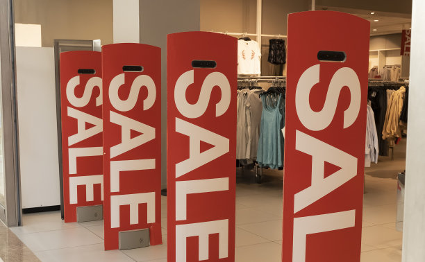红色海报上写着“减价出售”的字样。在时装店的购物橱窗里出售图片下载