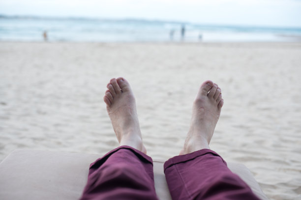 沙滩上有人躺在椅子上的脚图片下载