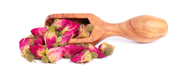 一堆干茶玫瑰花蕾在木勺，孤立在白色背景。玫瑰花茶。剪切路径。图片下载