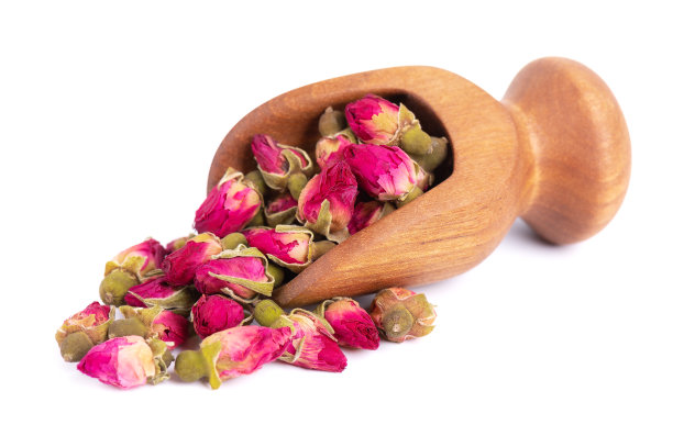 一堆干茶玫瑰花蕾在木勺，孤立在白色背景。玫瑰花茶。剪切路径。图片下载