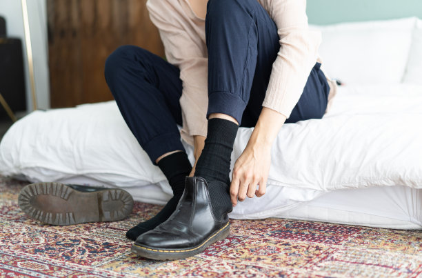 一个年轻人在旅馆里脱下他的黑漆皮靴子图片下载