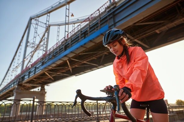 健康的千禧一代女性骑自行车时使用智能手机图片下载