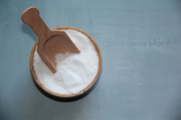 烹饪海盐，用木碗和木勺精制，孤立在浅蓝色背景上，俯视图。图片下载