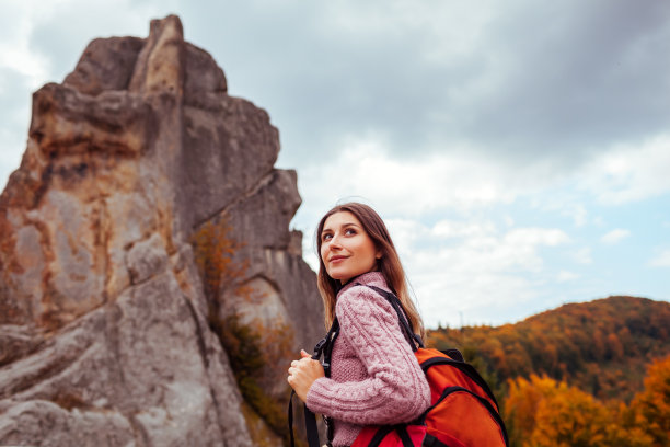 一名背着背包的女旅行者在喀尔巴阡山脉的岩石旁行走。乌克兰秋季旅游图片下载
